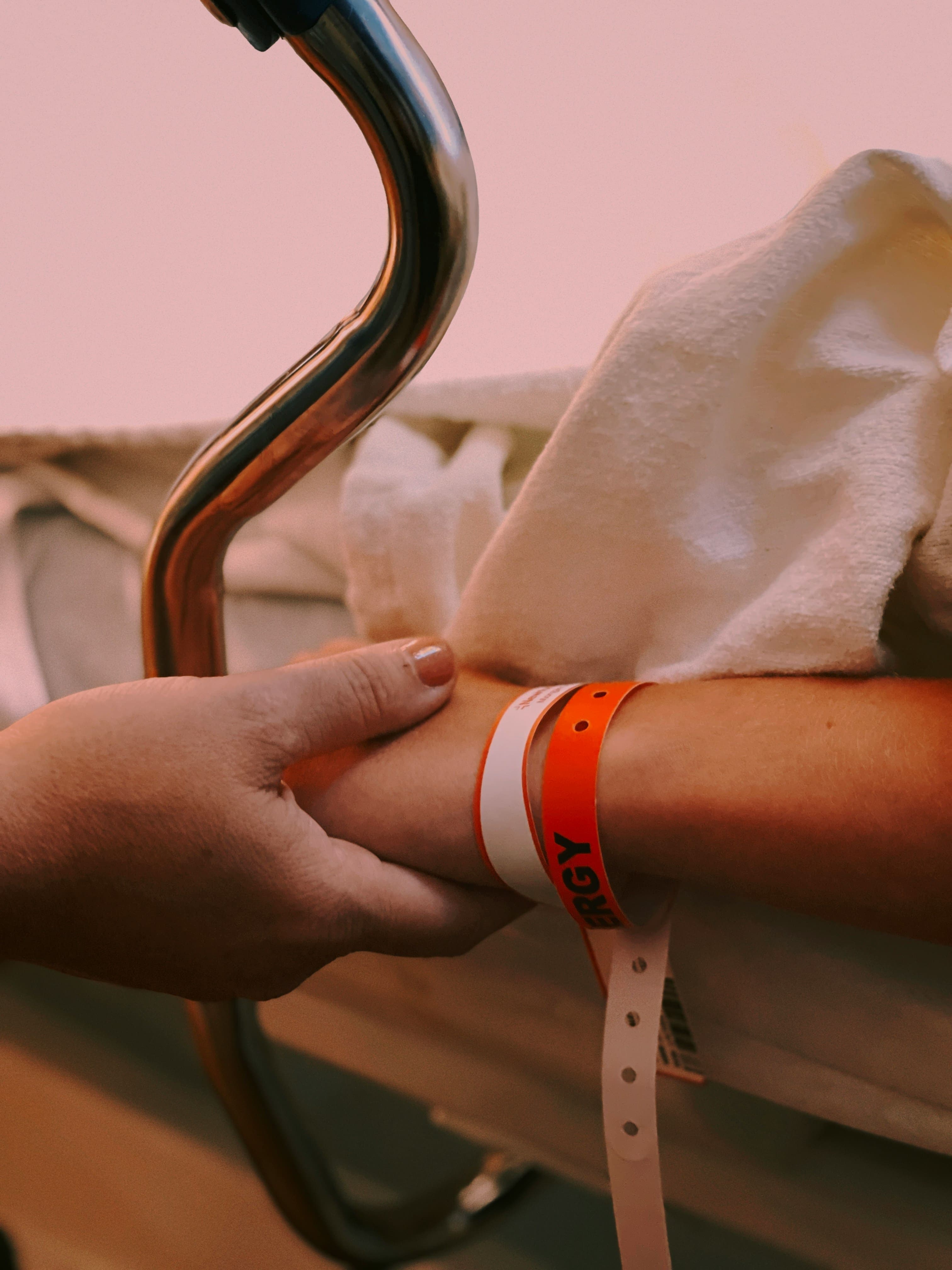Hand wird am Krankenbett gehalten – ist eine Kinderzusatzversicherung sinnvoll?